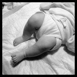 Low section of baby relaxing on bed