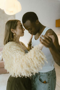 Romantic multiracial young couple dancing with each other at home