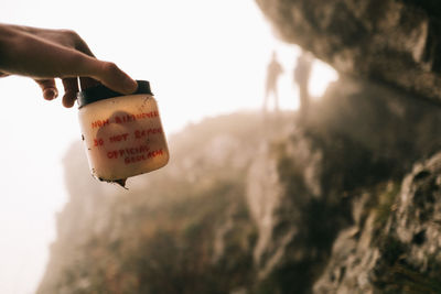 Low angle view of hand holding ice cream against sky