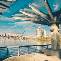Bridge over river by buildings against sky