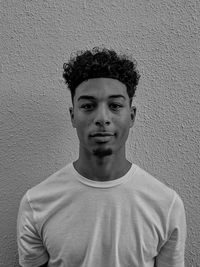 Portrait of young man standing against wall