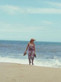 Woman walking at beach against sky