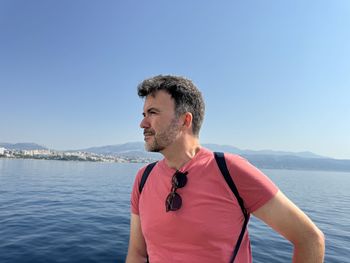 Side view of young man standing against sea