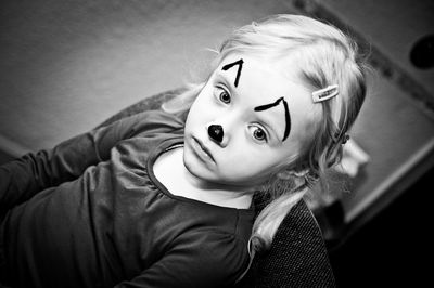 High angle view of girl with face paint sitting on armchair