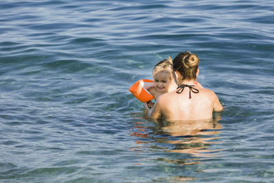 Rear view of women with girl swimming in sea