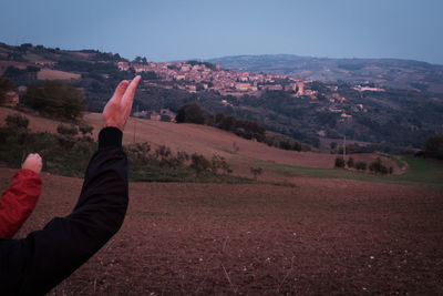 Midsection of man with arms raised on mountain