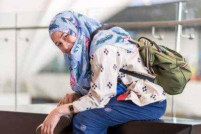 Portrait of smiling woman wearing hijab sitting indoors