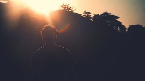 Rear view of silhouette man against sky during sunset