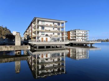 Reflection of building in lake against clear blue sky