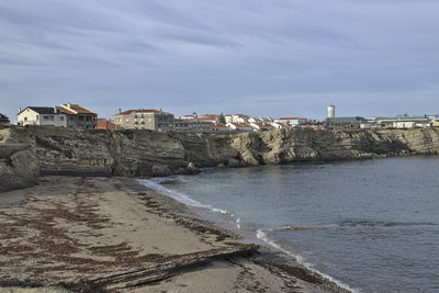 Buildings by sea against sky