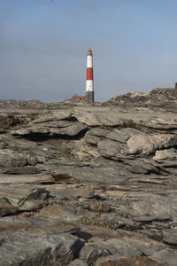 Lighthouse by sea against sky