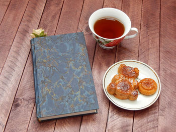 A cup of hot tea, a cupcake in the shape of a bear and a book with a rose as a bookmark