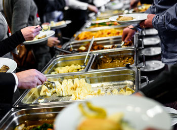 Cropped image of people taking food in cafeteria