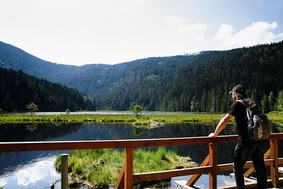 Woman standing on railing by mountain against sky