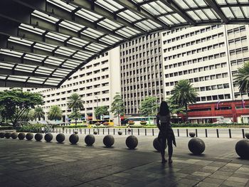 Rear view of man walking by buildings in city