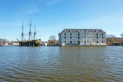 Buildings by river against sky in city