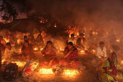 Praying at rakher upobash infront of burning candle and incense