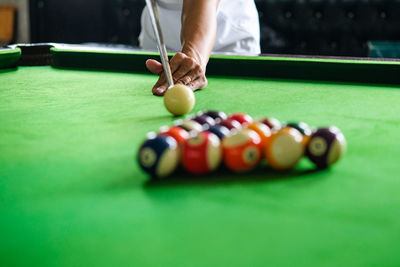 Midsection of man playing pool at club