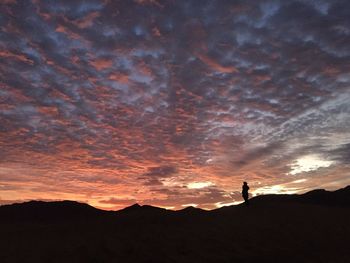 Silhouette man standing on mountain against sky during sunset