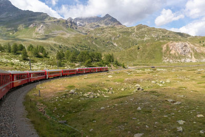 Scenic view of mountains and red train against sky