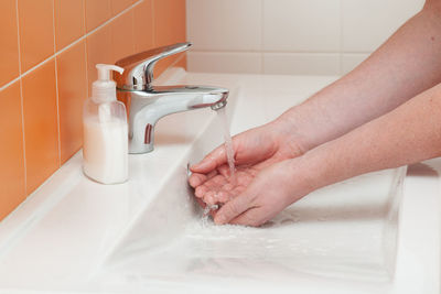 Close-up of person washing hands in sink