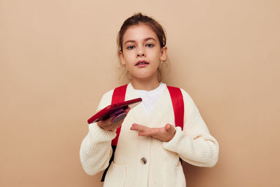 Portrait of smiling young woman standing against wall