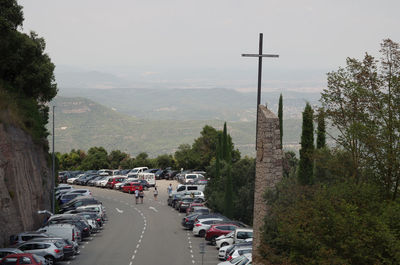 Cars on road by trees against sky in city