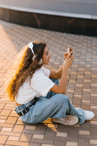Side view of woman sitting on footpath