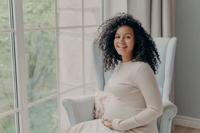 Portrait of smiling woman sitting on chair at home