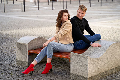 Full length of woman sitting on footpath