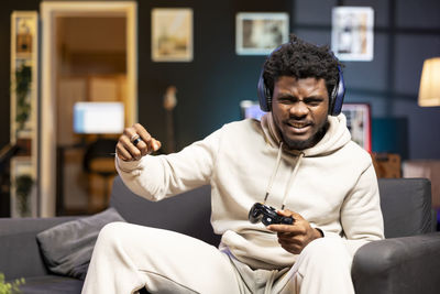 Young man using mobile phone while sitting at home