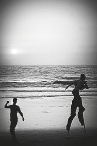 Silhouette people on beach against sky