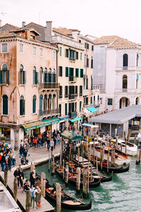 People on boats in canal by buildings in city