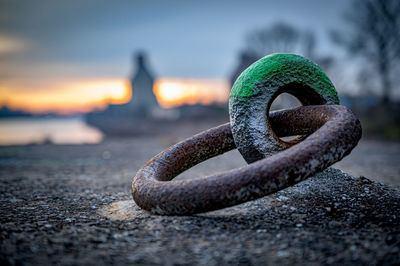 Close-up of rusty chain on shore against sky