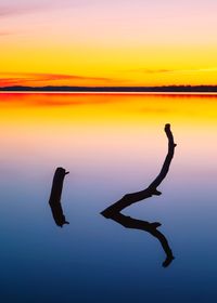 Silhouette person by sea against sky during sunset