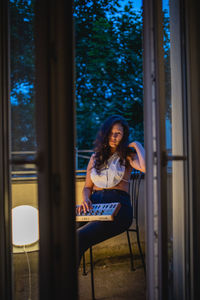 Young woman looking away while sitting on chair