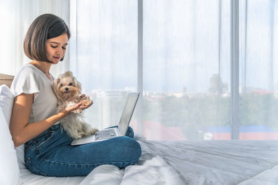 Woman with dog sitting on bed