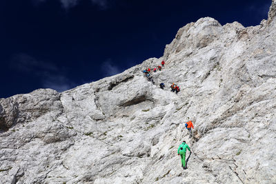 Low angle view of people on cliff against mountain