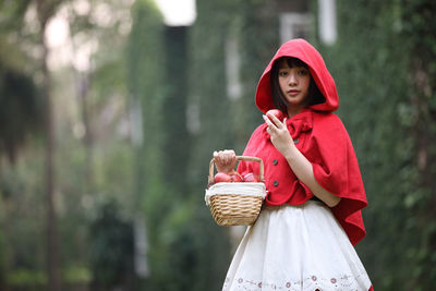 Young woman holding fruits in basket outdoors