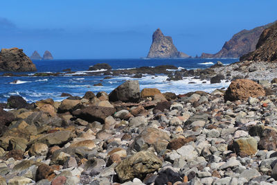 Rocks on beach against blue sky