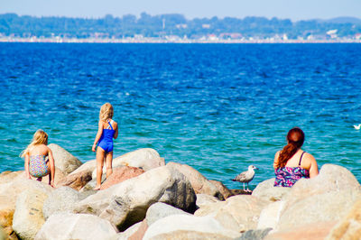 Rear view of people overlooking calm blue sea