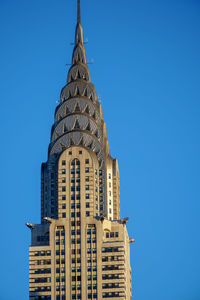 Low angle view of skyscraper against clear blue sky