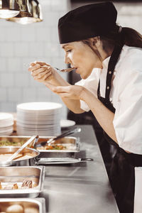 Kvinnlig kock smakar av i restaurangkök
