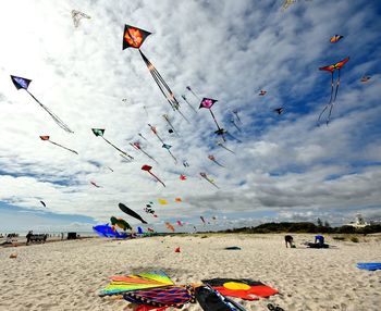 Kites flying over beach against cloudy sky