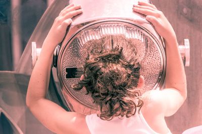 Rear view of girl looking through coin-operated binoculars