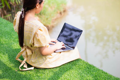 Midsection of woman using mobile phone while sitting on grass