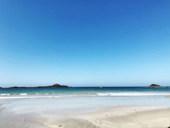 Scenic view of beach against clear blue sky