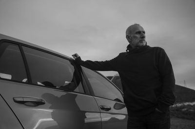 Side view of man standing in car