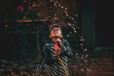 Boy holding squirt gun while standing outdoors