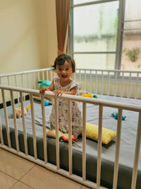 Portrait of baby girl looking through window at home